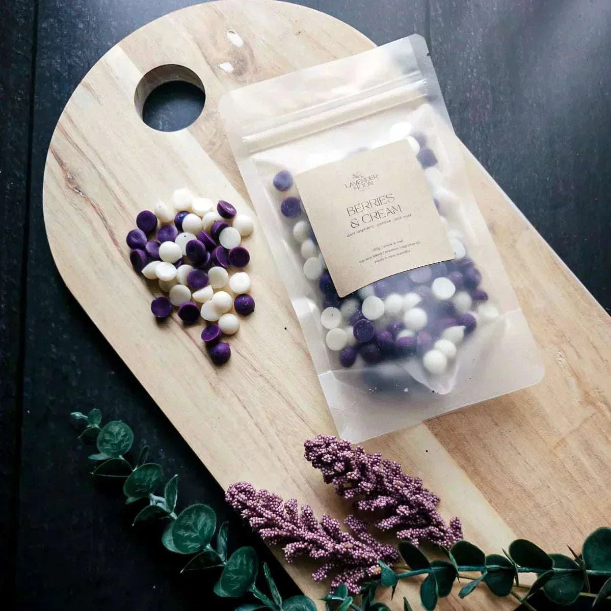 Berries & Cream wax melt with dark raspberry, jasmine, and pink musk on a wooden board.