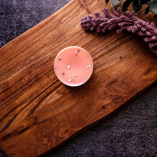 Gratitude Wax Melt on wooden surface with star-shaped accents, featuring mandarin, basil leaf, and jasmine scents.