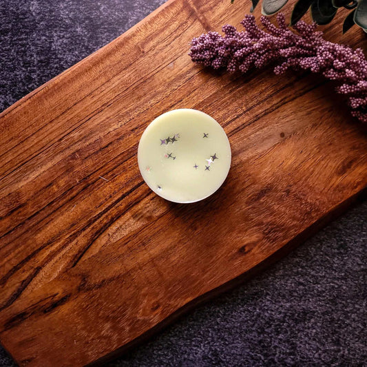 Manifest Waxmelt on wooden board, featuring lemongrass, citrus, and rose scents for mental clarity.
