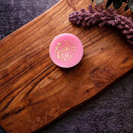 Pink watermelonade waxmelt on wooden surface with decorative flowers nearby.