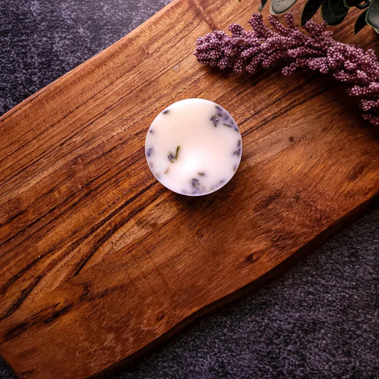 White Tea & Lavender Waxmelt on wooden board with lavender sprigs, featuring a soothing floral aroma of bergamot, jasmine, and lavender.