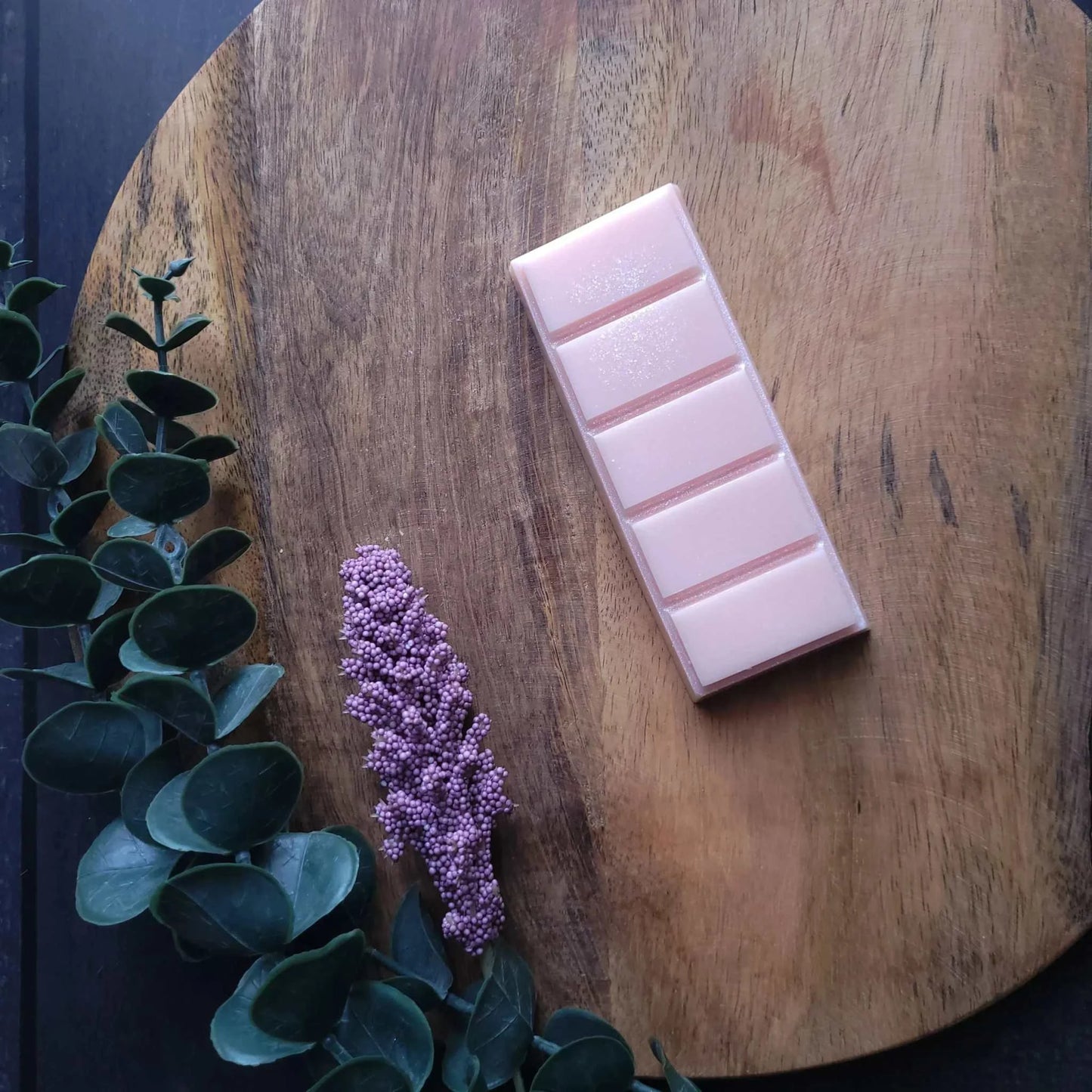 Gratitude Wax Melt with mandarin, basil leaf, and jasmine on a wooden board.
