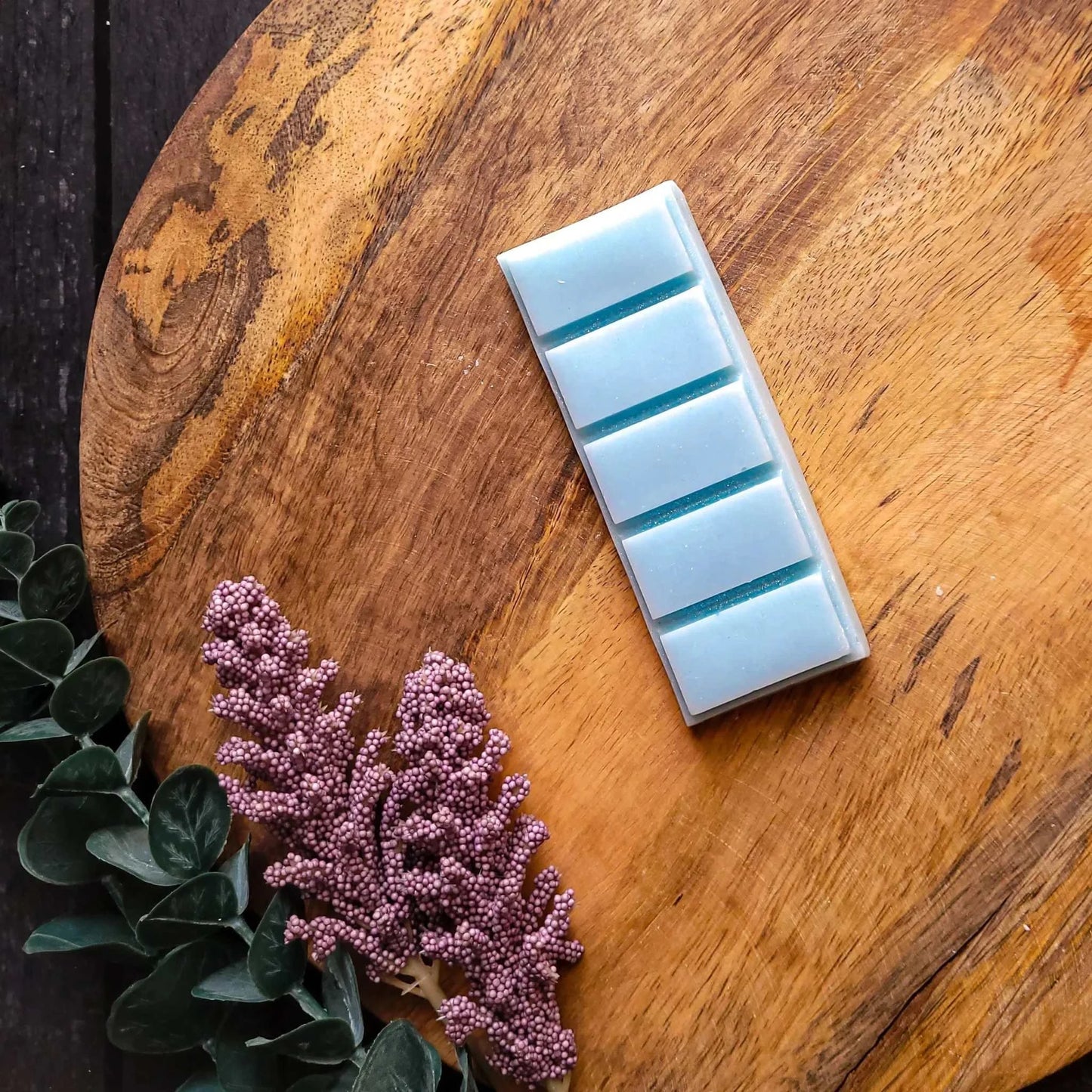 Meditate Waxmelt on wooden table with flowers; honeydew, cucumber, freesia fragrance; vegan soy wax blend.