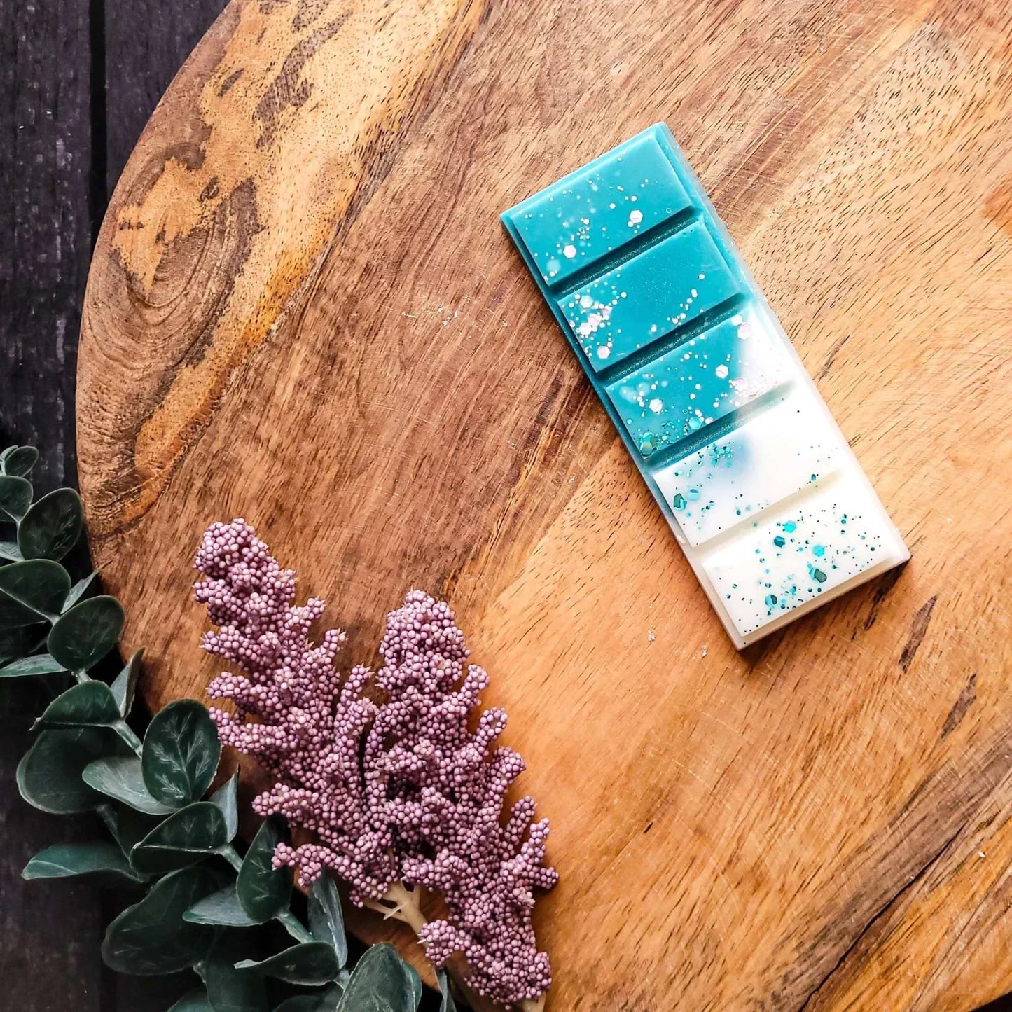 Ocean Mist Waxmelt with wild lavender, geranium, and honey on a wooden surface, surrounded by foliage, evoking a coastal breeze.