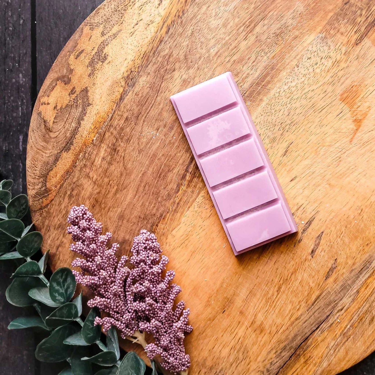Tranquility Waxmelt in lavender shade on wooden surface with greenery and flowers.