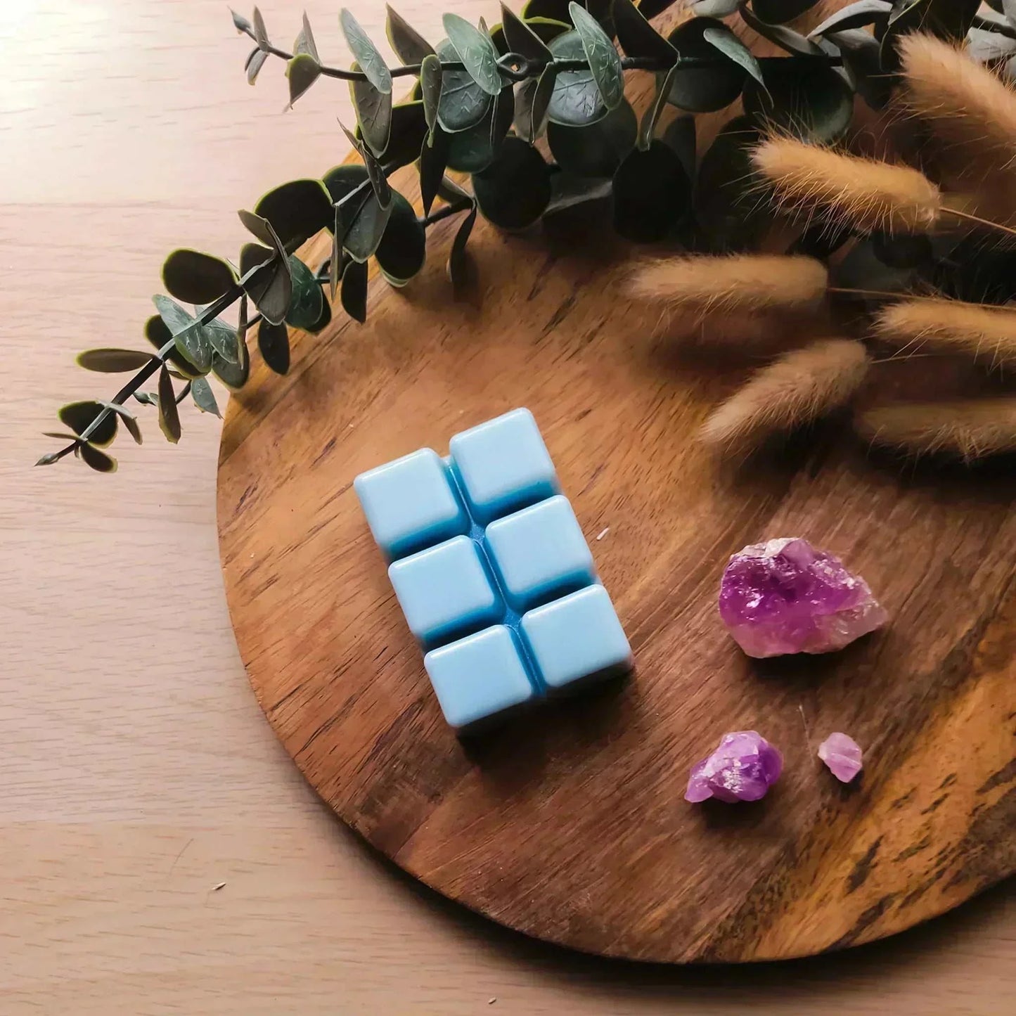 Vegan-friendly soy wax melt pack with purple crystals on wooden tray.
