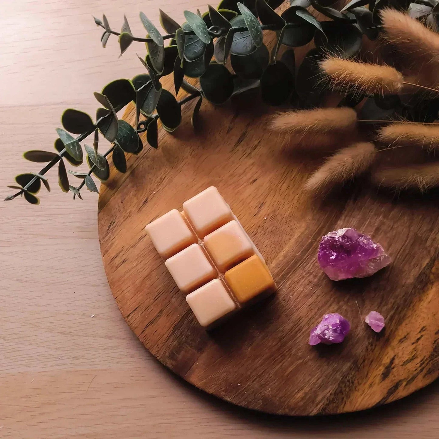 Vegan-friendly soy wax melt pack on wooden platter with greenery and crystals.