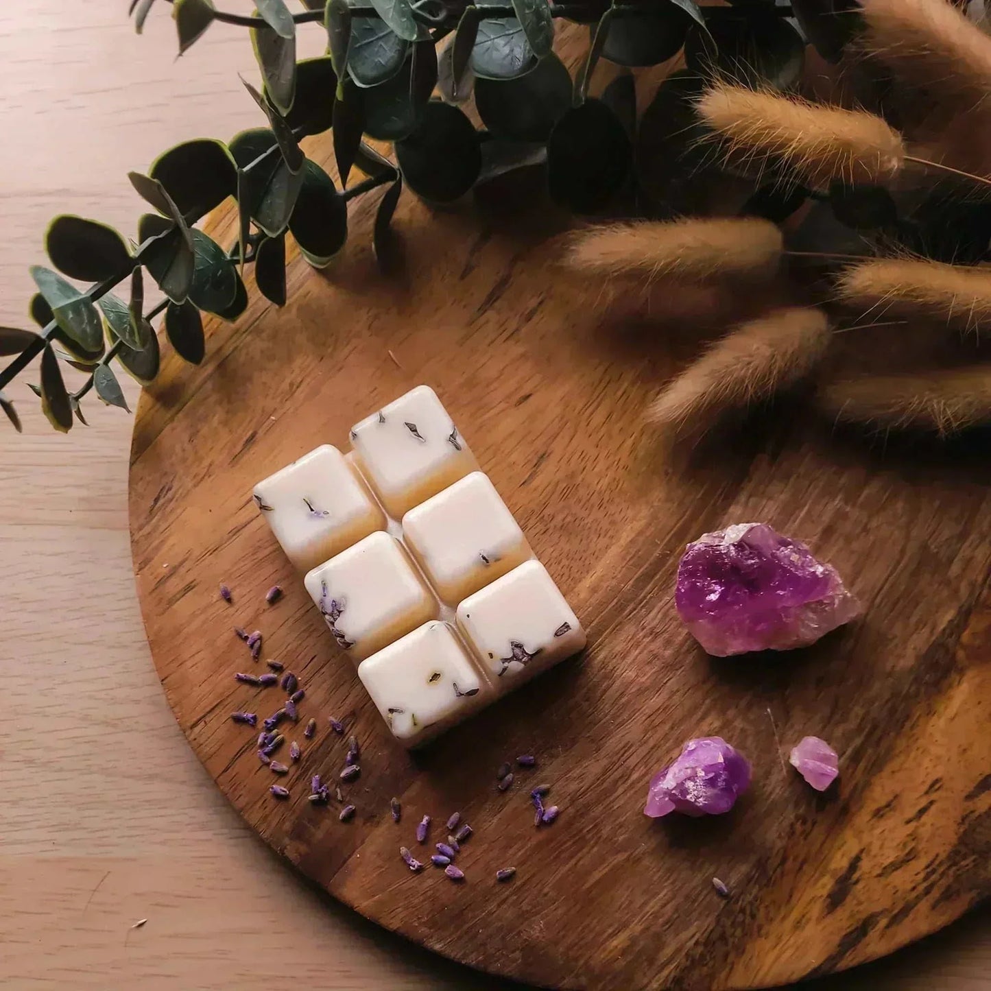 Vegan-friendly soy wax melts on a wooden board with lavender and crystals.