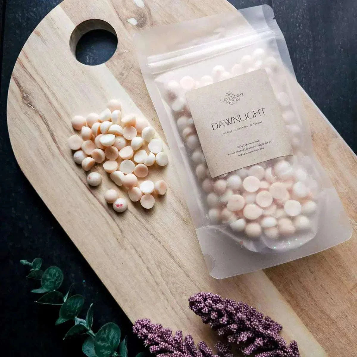 Vegan-friendly Dawnlight Wax Melt with orange, rosewood, and patchouli scent on wooden board.