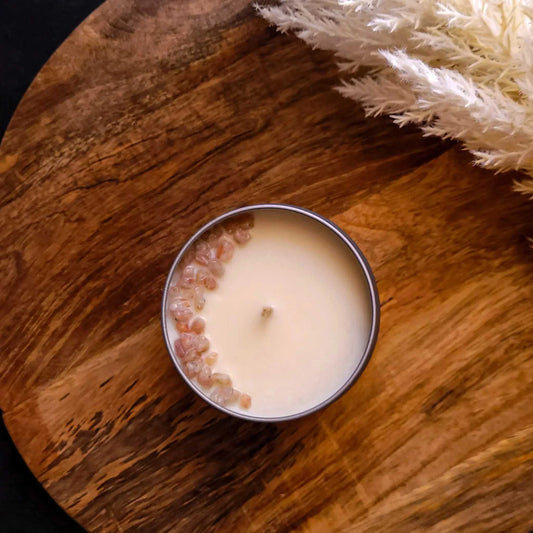 Glow Candle from Wellness Range with grapefruit, chamomile, sandalwood, and sunstone chips, on a wooden surface.