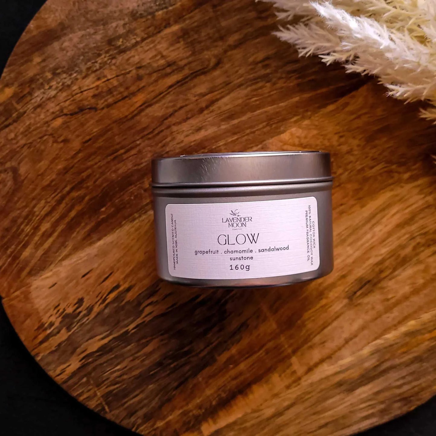 Glow Candle from Wellness Range on wooden surface, featuring a blend of grapefruit, chamomile, and sandalwood; decorated with natural sunstone chips.