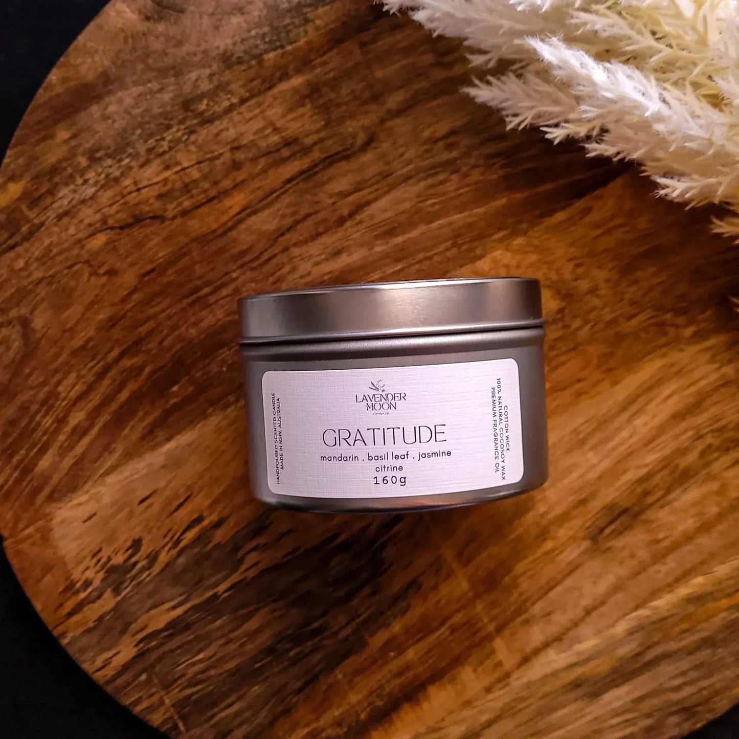 Gratitude Candle in tin on wooden surface, featuring mandarin, basil leaf, and jasmine scent.