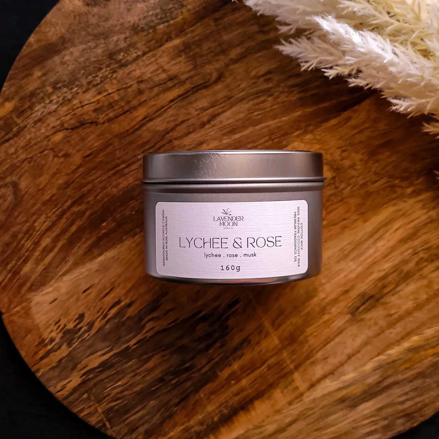 Lychee & Rose Candle on wooden surface, emitting a lychee, rose, and musk fragrance.