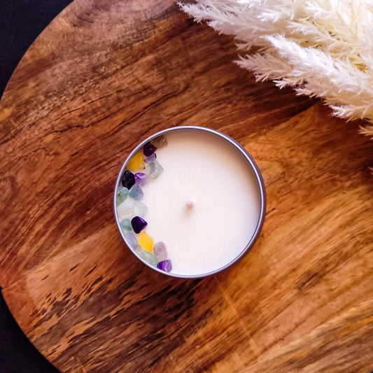 Manifest Candle with Rainbow Flourite on a wooden surface.