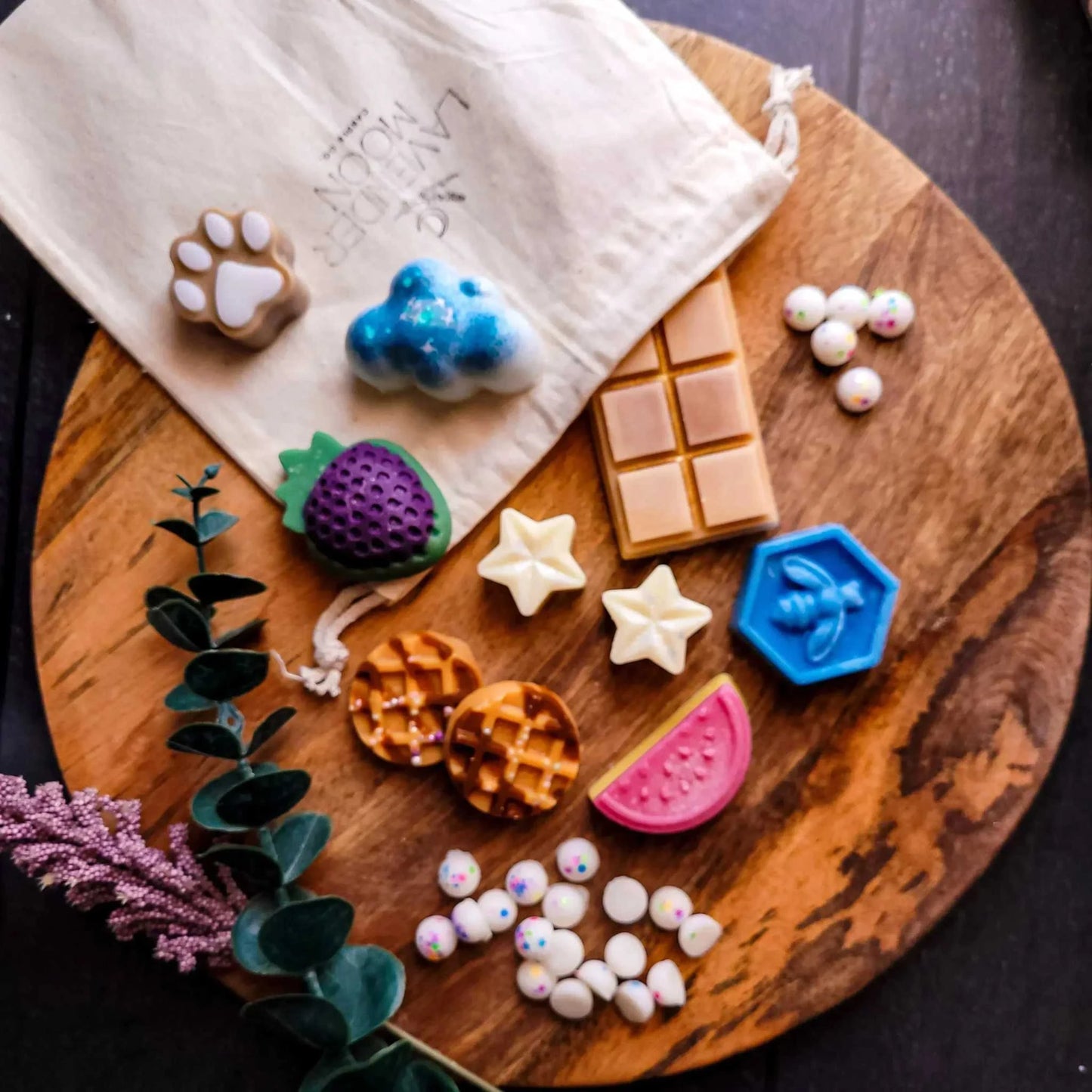 Mystery Melt Bag with assorted wax melts on wooden board, featuring novelty shapes and vibrant colors.