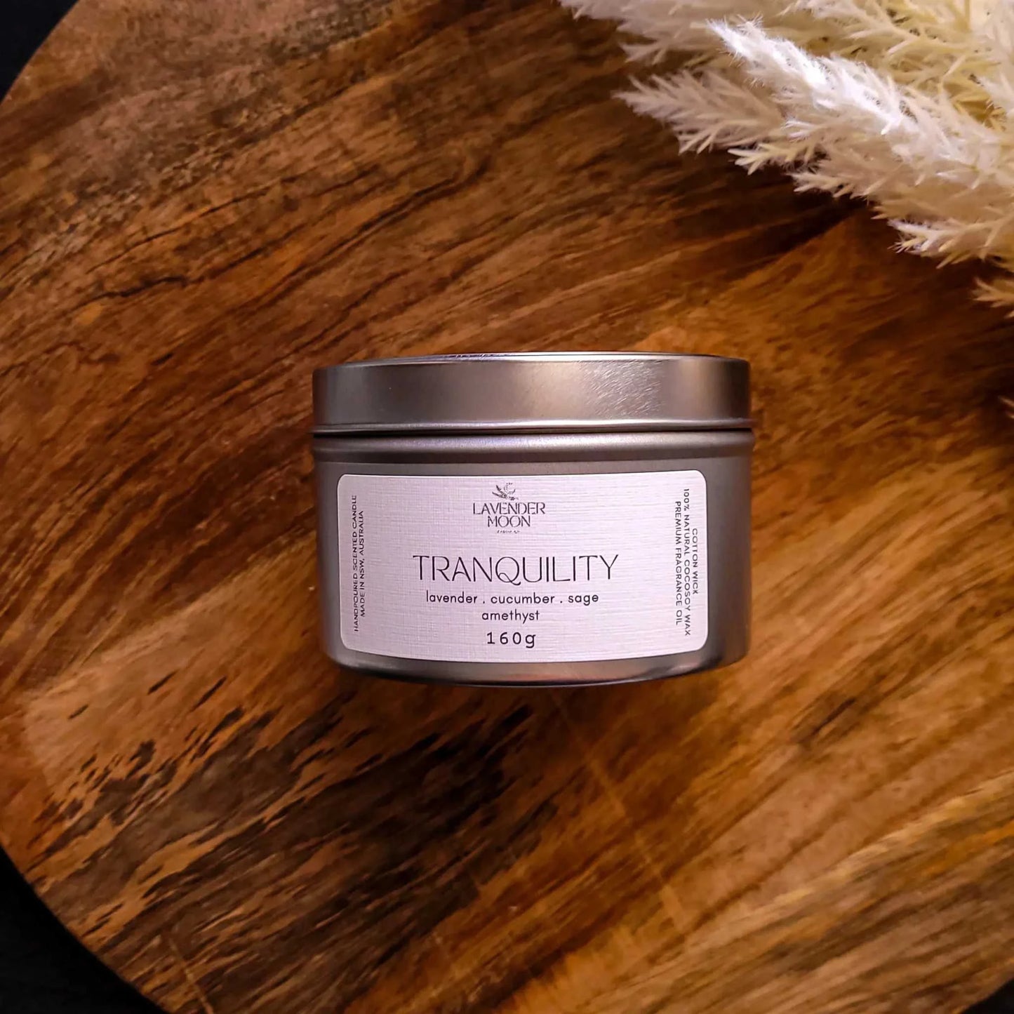 Tranquility Candle tin with lavender, cucumber, and sage blend on wooden surface.