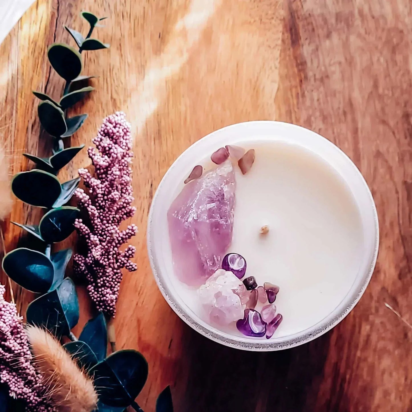 Tranquility Candle with amethyst crystals, surrounded by lavender and sage on a wooden surface.
