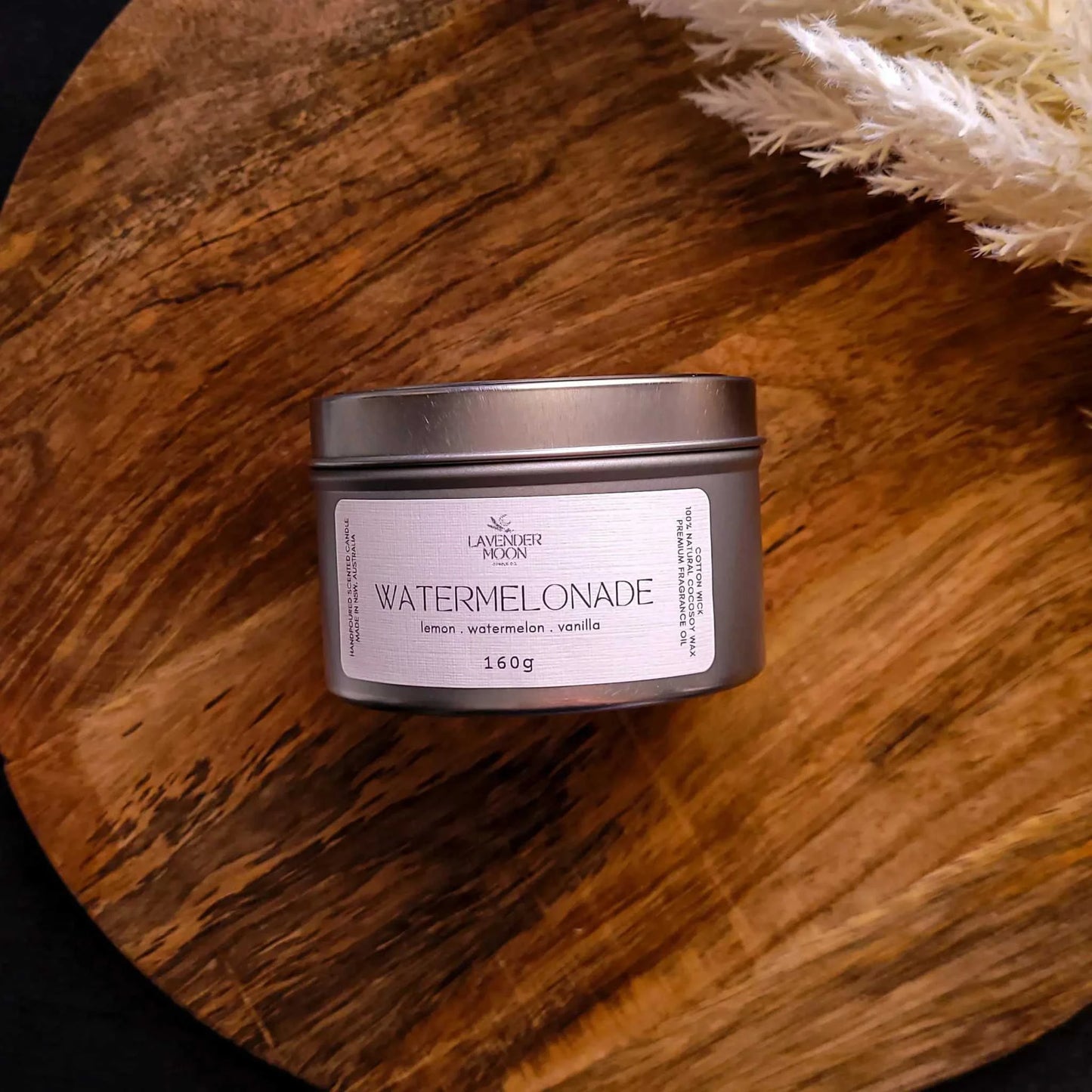 Watermelonade Candle in tin, featuring lemon, watermelon, and vanilla scents on a wooden background.