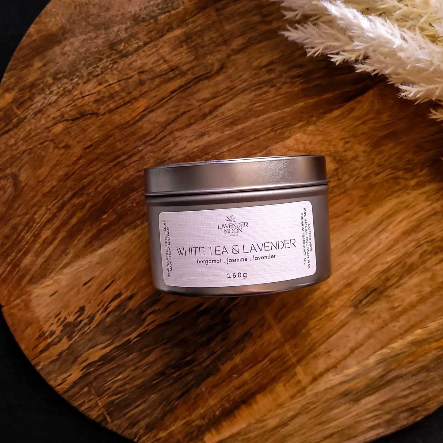 White Tea & Lavender Candle with bergamot, jasmine, lavender scent in silver tin on wooden surface.