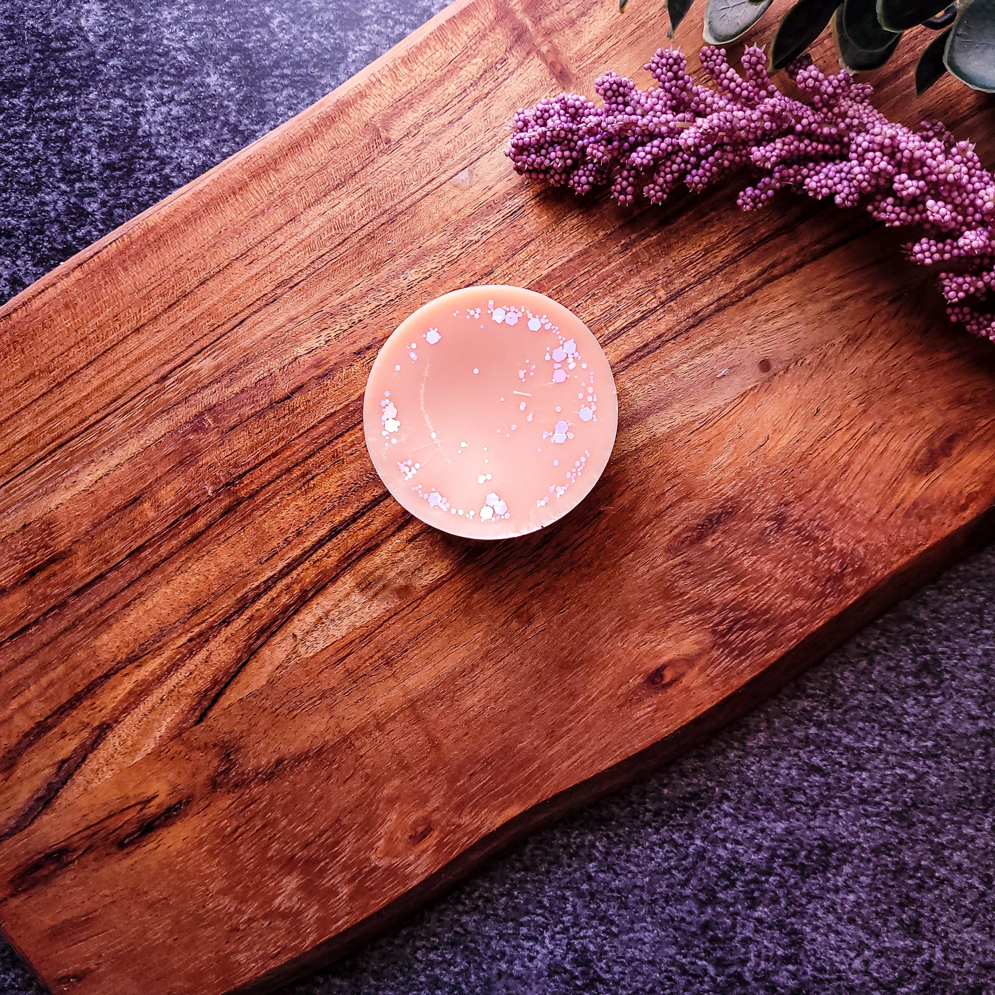 Vegan-friendly Dawnlight wax melt with orange, rosewood, and patchouli on wooden board.