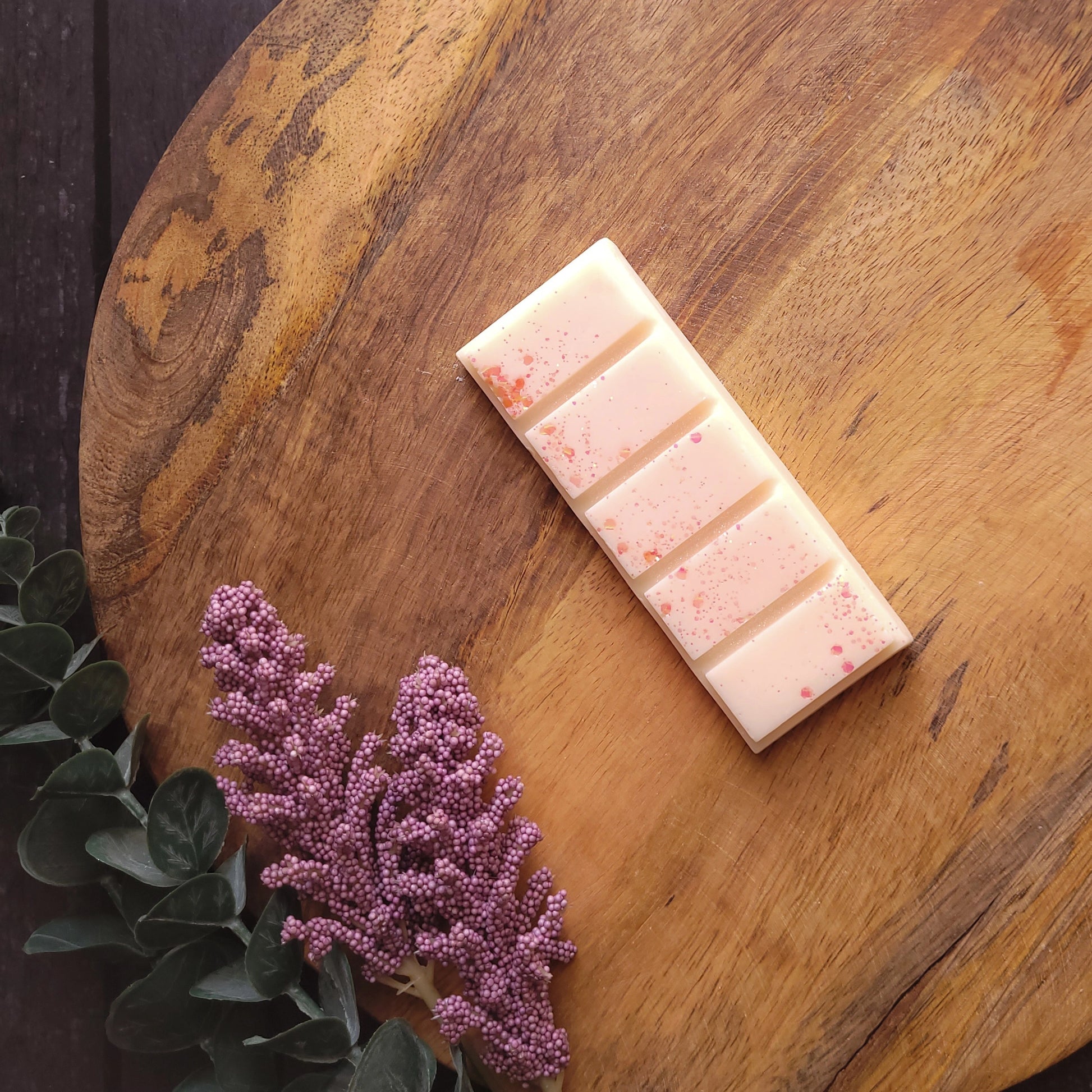 Vegan-friendly Dawnlight wax melt with orange, rosewood, and patchouli scent on a wooden board.