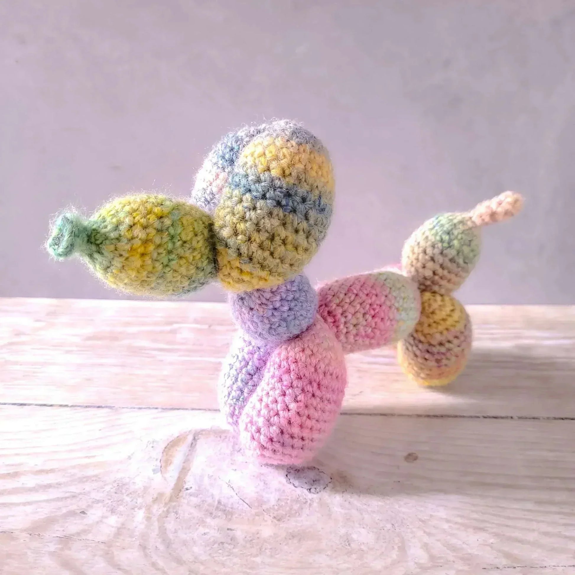 Balloon dog amigurumi toy in rainbow colors made from acrylic and wool blend.