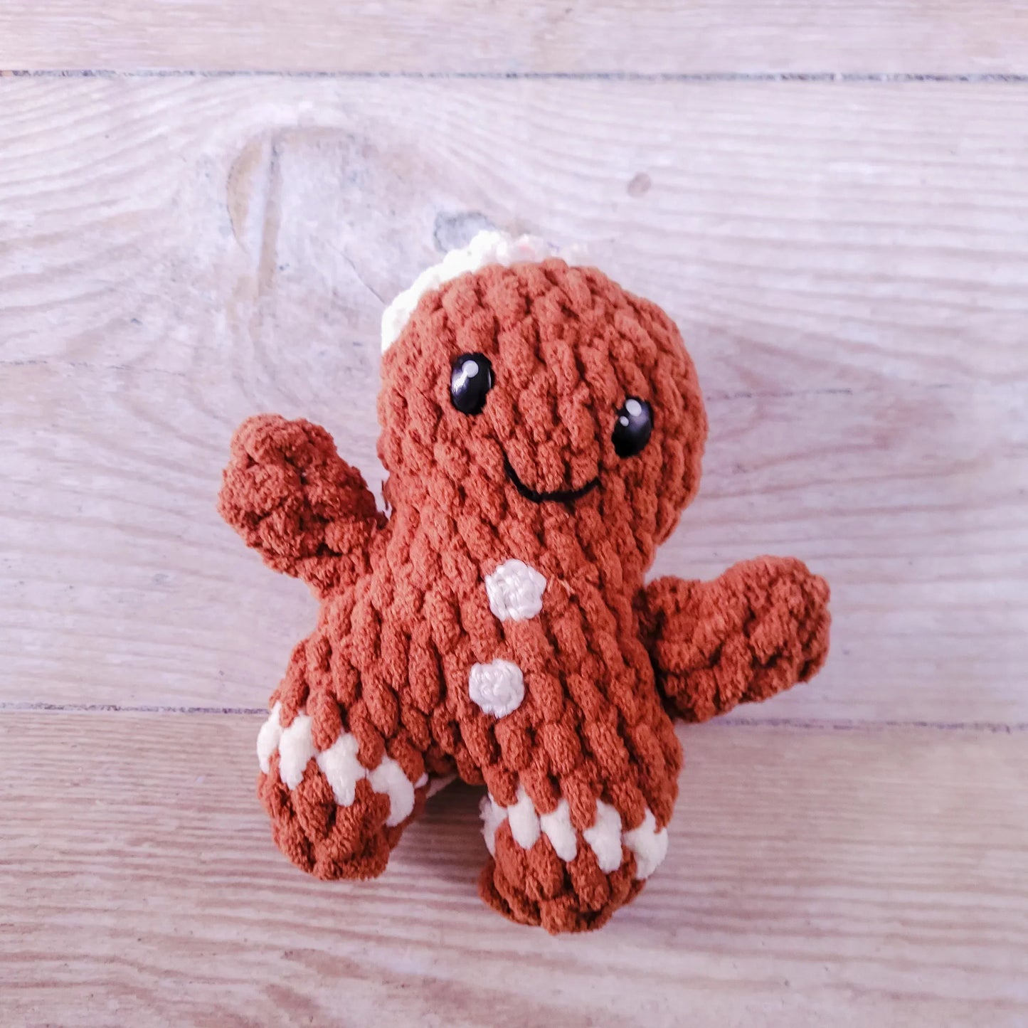 Hand-crocheted gingerbread man amigurumi toy with icing and sprinkles, made from polyester chenille and acrylic yarn.