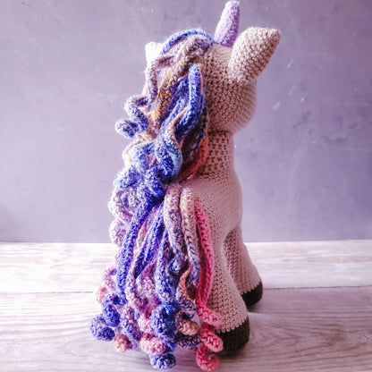 Hand-crocheted unicorn amigurumi soft toy with glittery horn and vibrant rainbow mane.